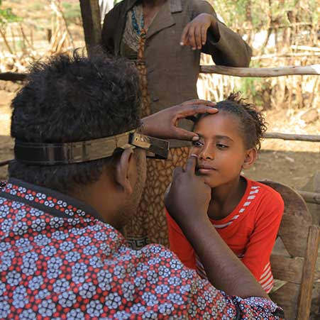 Ein Mann untersucht die Augen eines Mädchens.