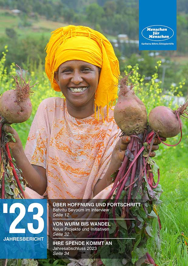 Cover des Jahresberichts 2023, das eine Frau zeigt, die in einem Feld sitzt, rote Rüben in den Händen hält und in die Kamera lacht
