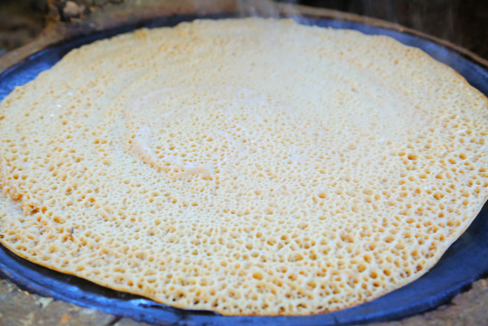 Injera, Sauerteigfladen aus Teff, in der Pfanne zum Backen.