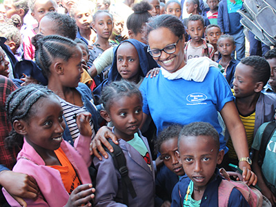 Bahritu Seyoum im blauen Menschen für Menschen-Shirt steht lachend in einer Traube äthiopischer Schülerinnen und Schüler