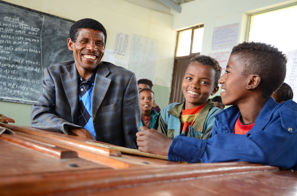 Haile Gebrselassie mit Schulkindern in einem Klassenraum.