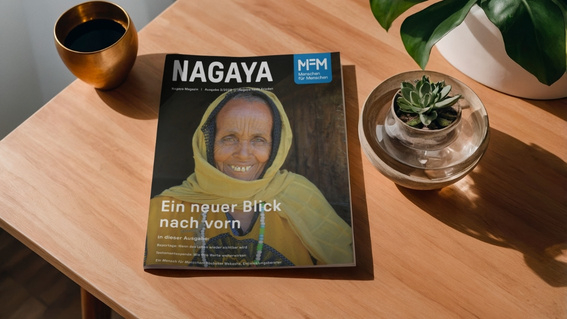 Das Cover des Nagaya-Magazins, Ausgabe 3/2026, zeigt eine ältere Frau, die sich lächelnd an einen Türstock lehnt und direkt in die Kamera blickt.