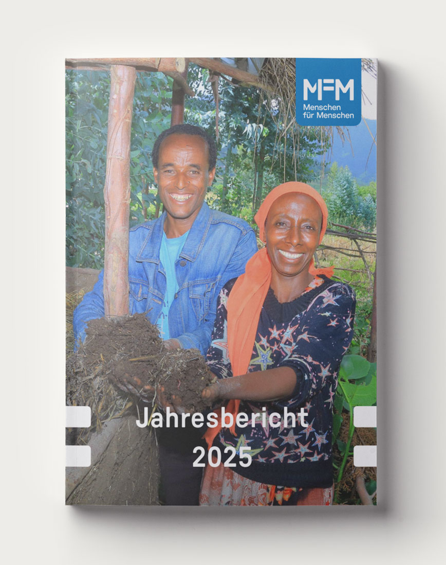 Das Titelbild des Jahresberichtes 2025 zeigt eine Frau und einen Mann, die in ihrem Garten frische Erde aus einem Wurmbeet entnehmen.