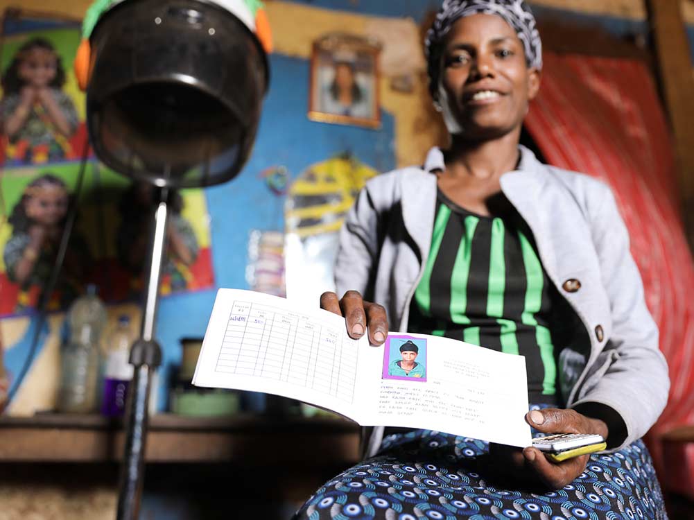 Friseurin in Äthiopien zeigt Buch ihrer Kreditgruppe