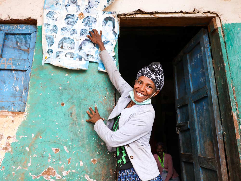 Friseurin in Äthiopien steht vor ihrem laden und hängt Werbung auf