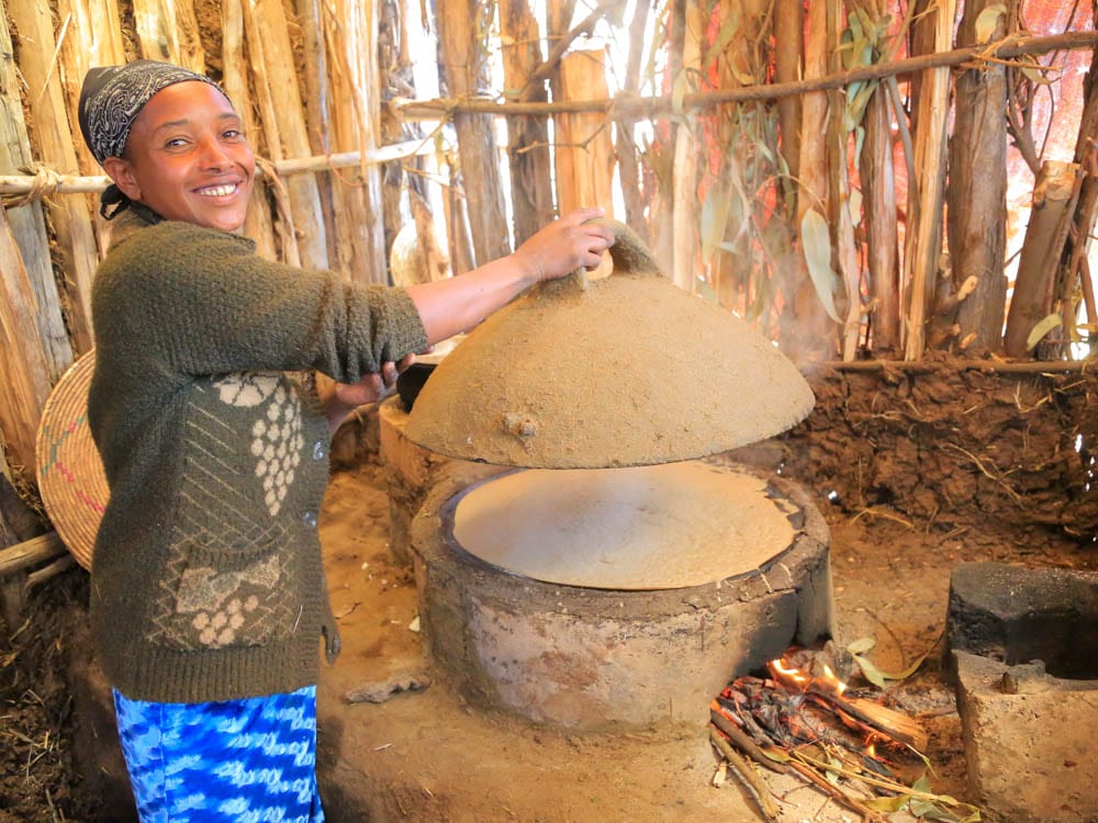 Frau in Äthiopien lacht neben ihrem neuen holzsparenden Ofen