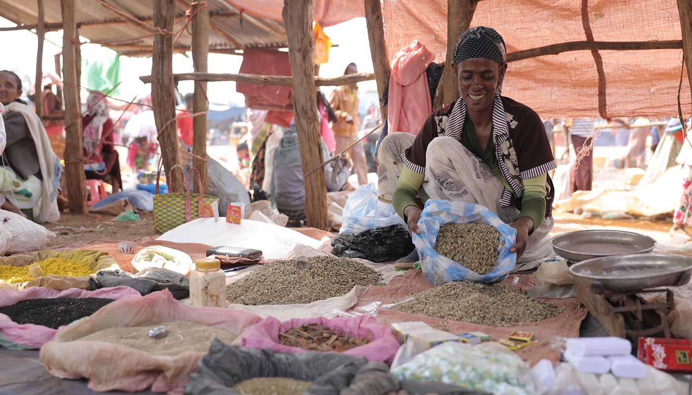 Eine äthiopische Frau am Markt hält ein Säckchen voll grüner Kaffeebohnen in der Hand