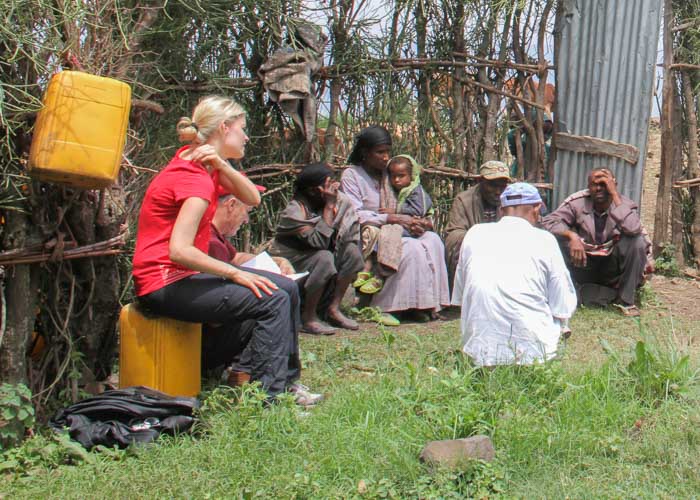 Weisse Frau sitzt in Äthiopien in einer Gruppe von Menschen