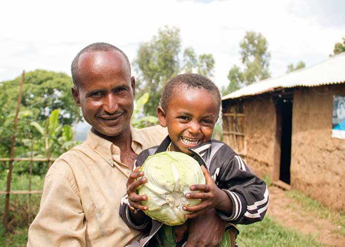Mann mit Sohn im Arm der einen Kohl hält in Äthiopien